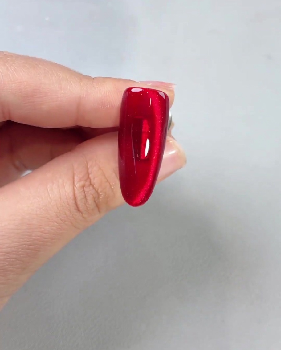 Un top coat lucido applicato su ununghia magnetica rossa finita, che mostra unelevata brillantezza.