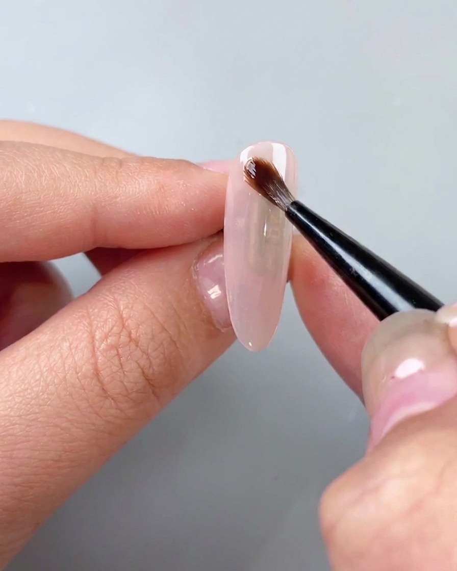 Un pennello applica un gel trasparente per sfumature acquerello sopra una base coat.