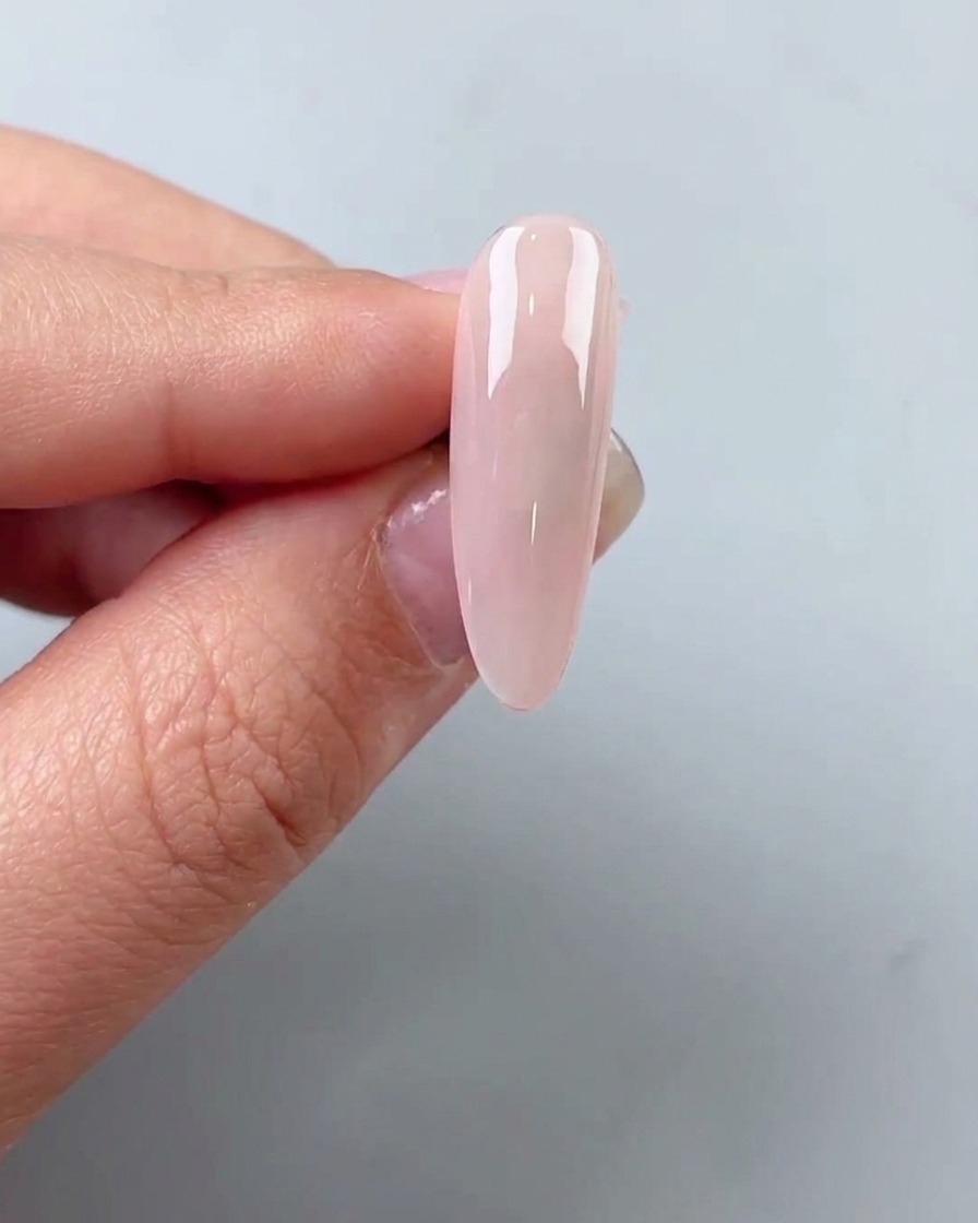 Piccole scaglie di foglia oro posizionate sulla superficie di ununghia con una pinzetta.