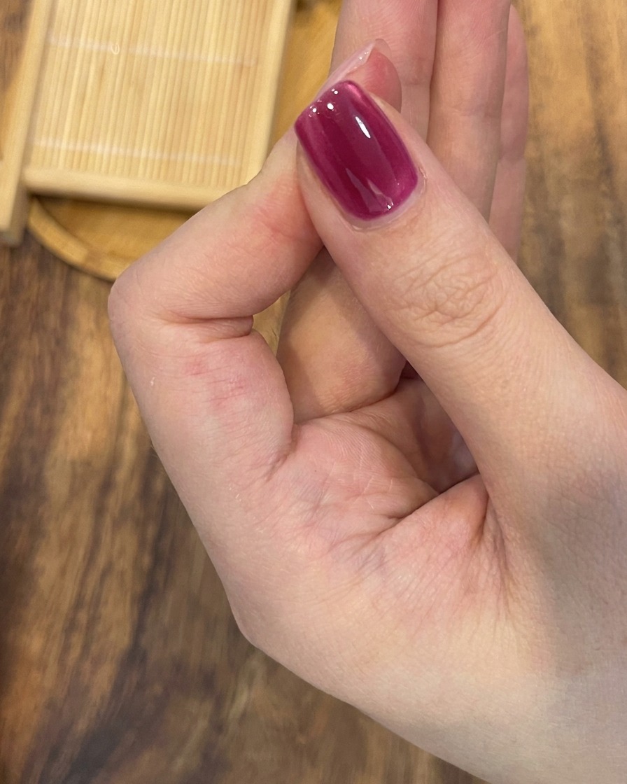 Primo piano di un magnete posizionato in diagonale sopra ununghia in gel magnetico per esaltare la luminosità e la definizione delleffetto cat-eye.