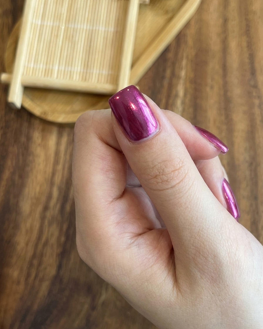 Primo piano che mostra luso di un magnete per centrare con precisione la luminosa linea cat-eye su ununghia rosso rosa.