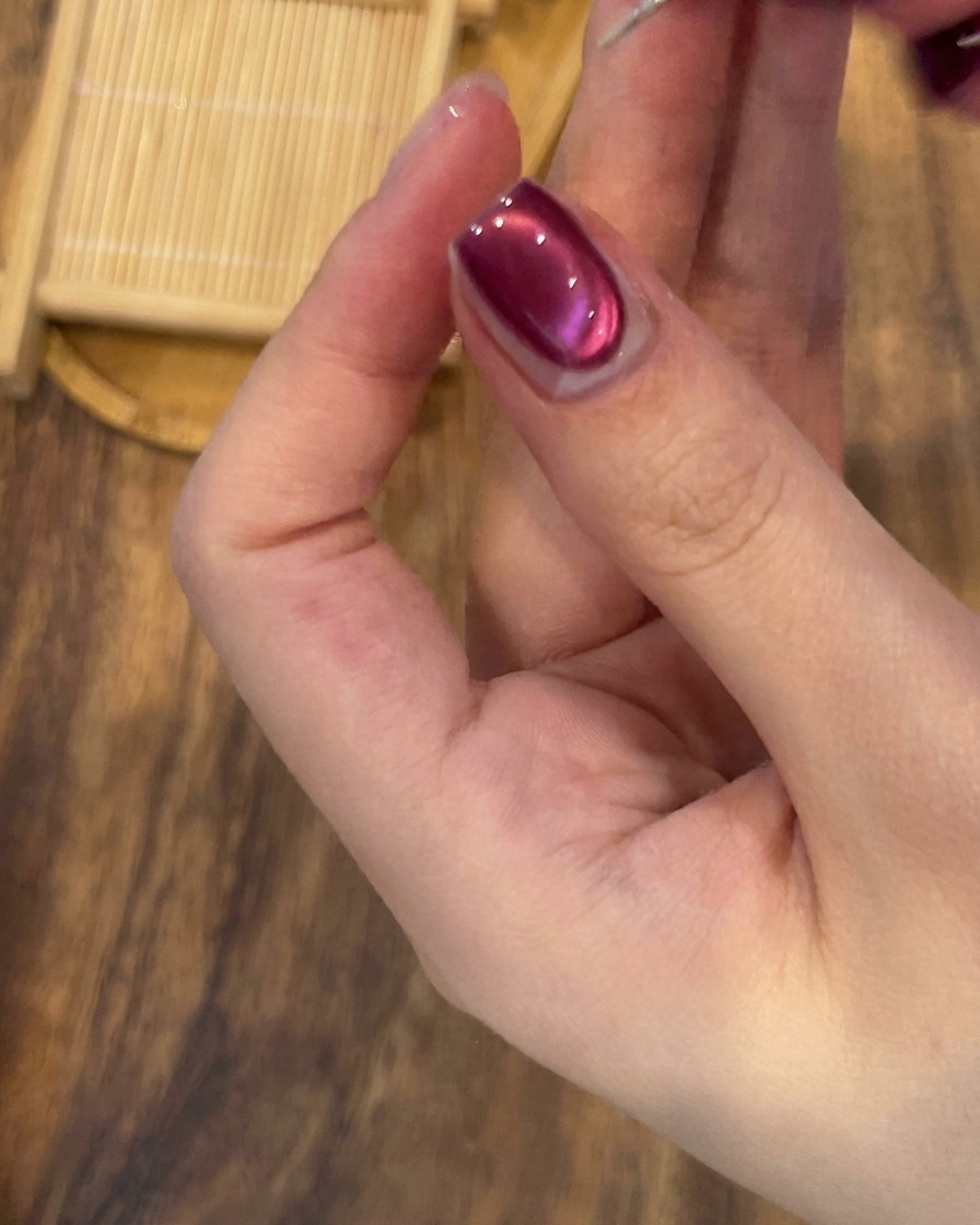 Un pennello di precisione che applica una sottile linea di gel glitter argento lungo la base di ununghia in gel cat-eye.