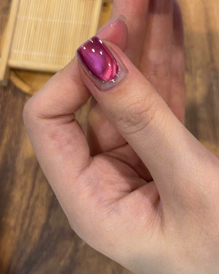 Un pennello che stende un top coat trasparente e lucido sopra il design finito con cat-eye e glitter.