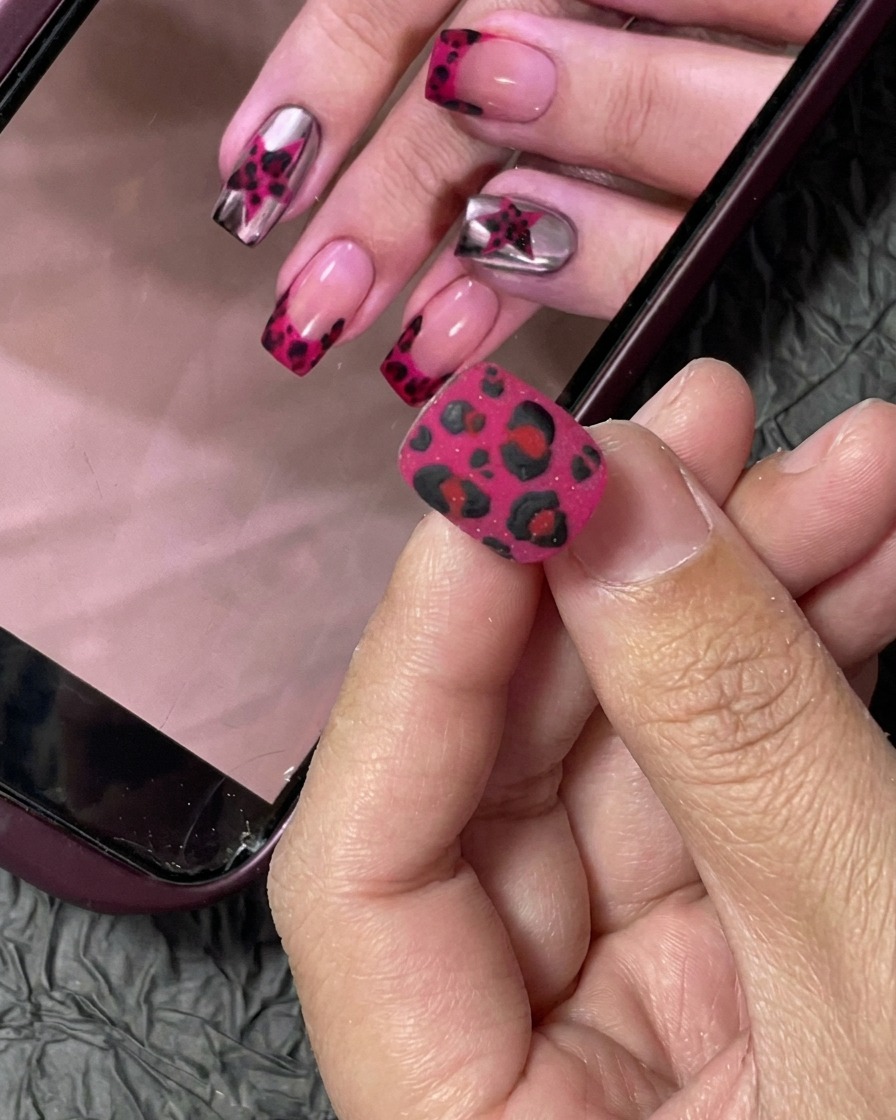 Una piccola tip per unghie rivestita con un vivace smalto gel fucsia applicato con un pennello professionale.