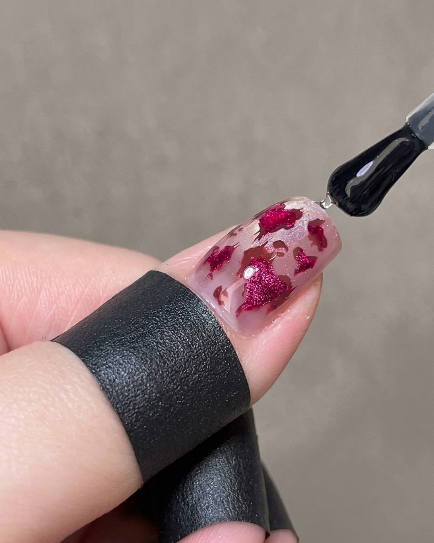 Un pennello che applica uno strato spesso di gel lucido trasparente sopra ununghia decorata per incapsulare il design.