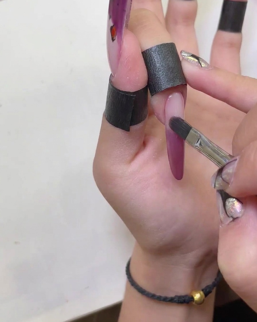 Un pennello utilizzato per modellare e levigare ordinatamente i bordi della french in gel cat-eye rosso.
