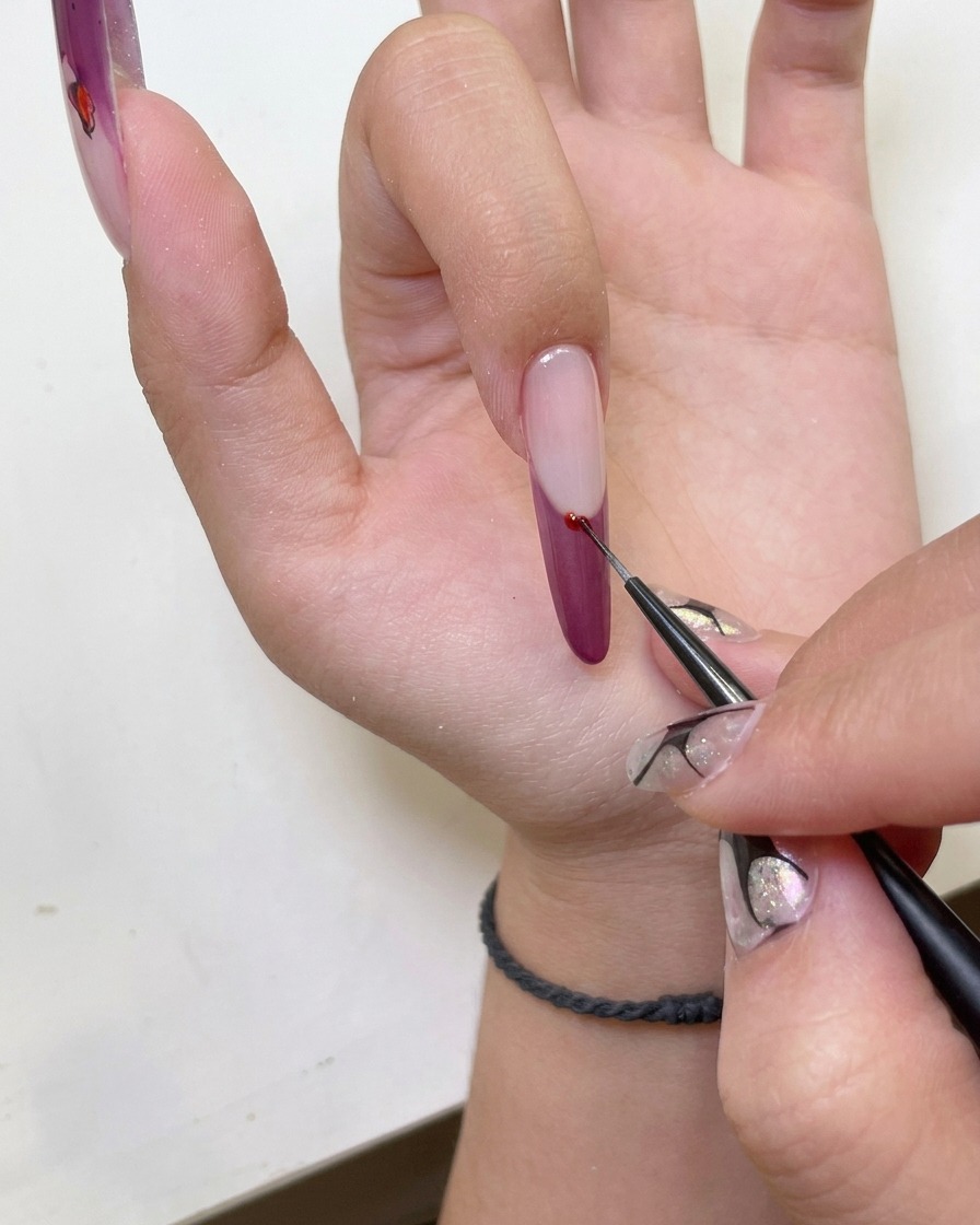 Primo piano di una mano con nail art french cat-eye inserita in una lampada UV per unghie.