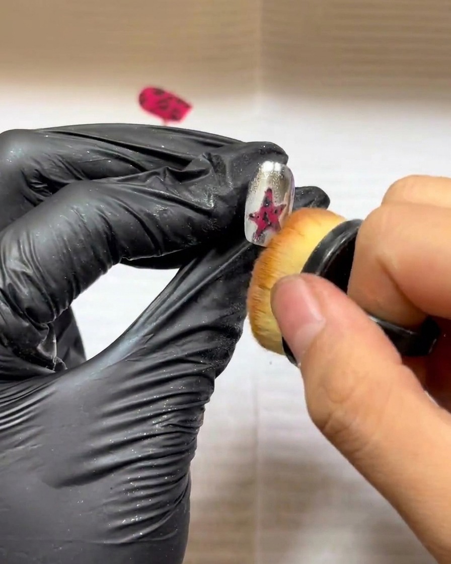 Un piccolo pennello da trucco usato per spazzare via delicatamente la polvere in eccesso da un design a stella texturizzato.