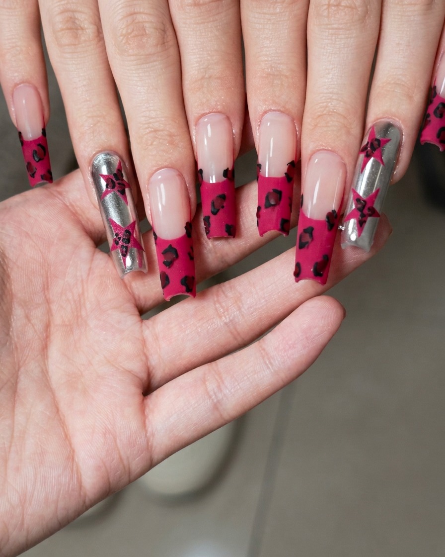 Primo piano di un pennello fine per nail art che dipinge una piccola stella nera su una superficie metallica argentata.