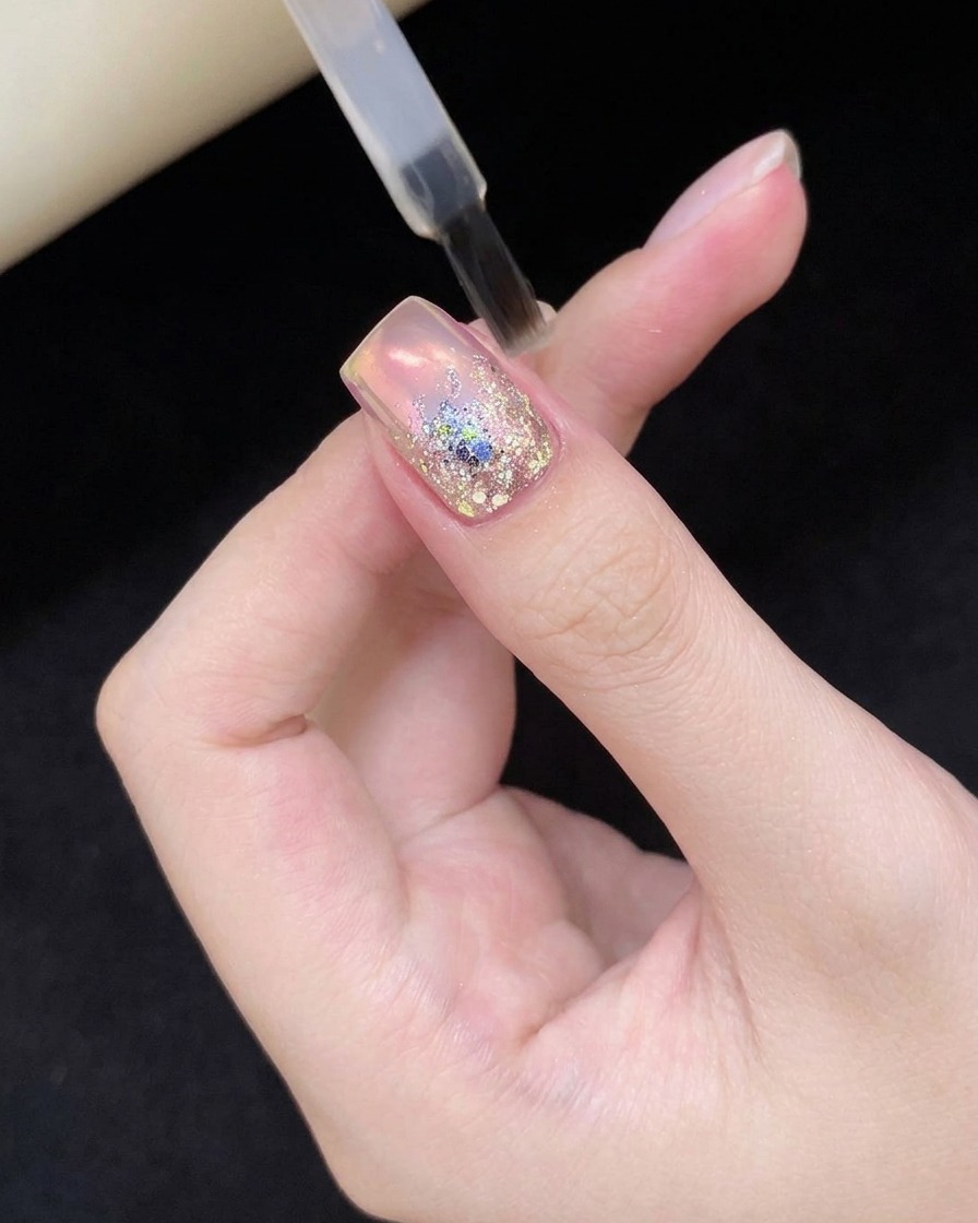 Ununghia con nail art glitterata tenuta allinterno di una lampada professionale per polimerizzazione UV/LED.