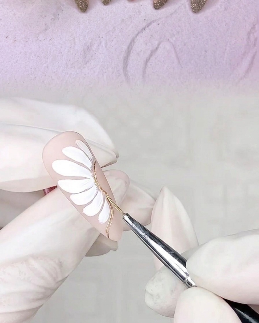 Una mano con ununghia decorata inserita in una lampada UV per polimerizzare i contorni in gel appena applicati.