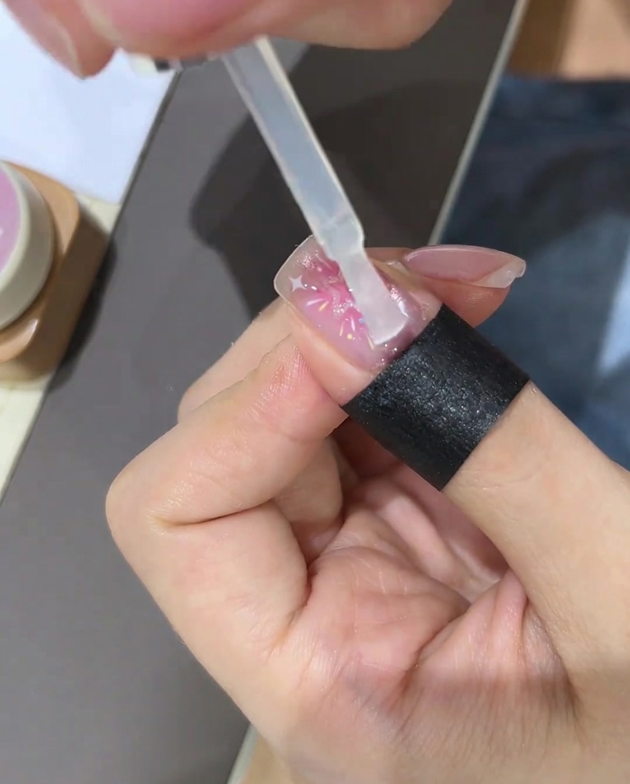 Un pennello che applica un top coat trasparente sopra il design stellato completato.