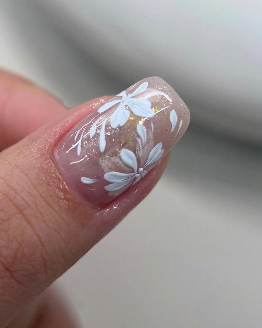 Un pennello piatto ammorbidisce il bordo del gel bianco su ununghia.