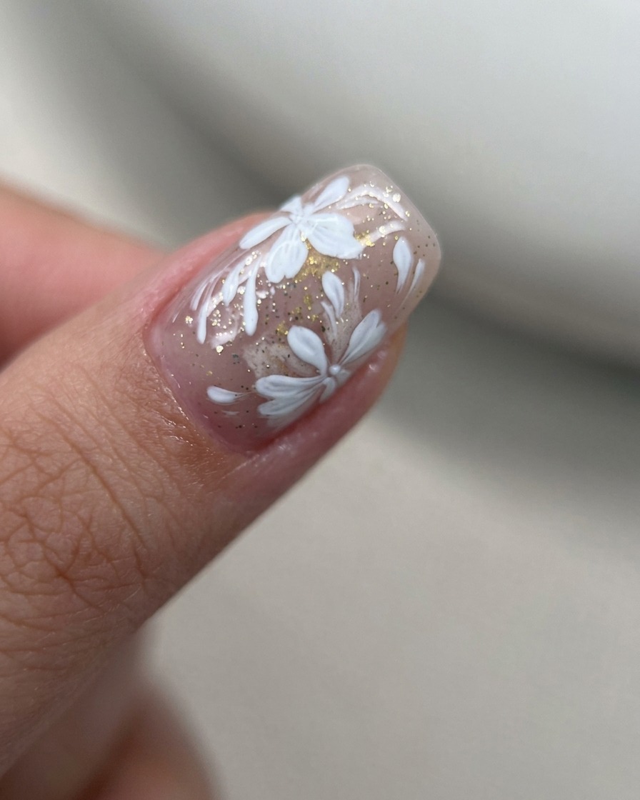 Macro di petali di fiori in gel bianco dipinti in un cluster concentrato su ununghia nude.