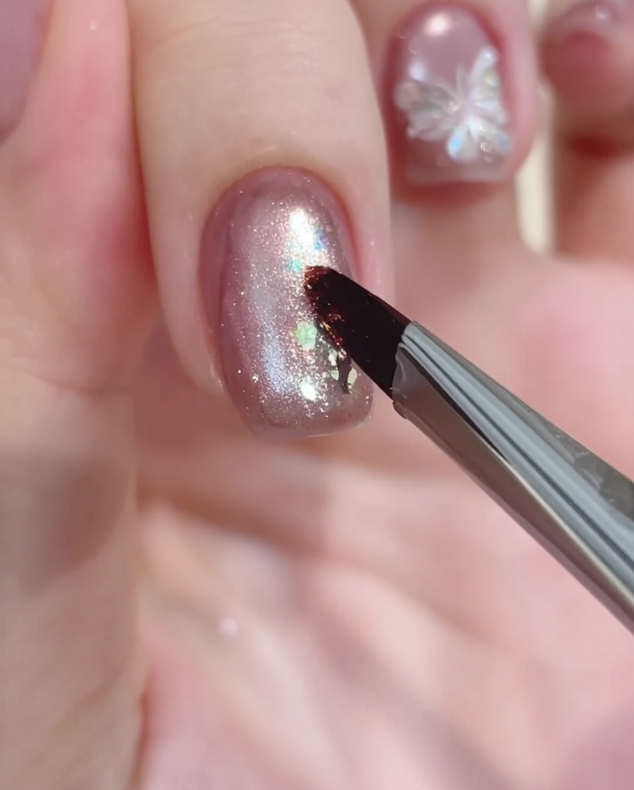 Un pennello da nail art deposita una goccia di gel bianco come punto di partenza del fiore.