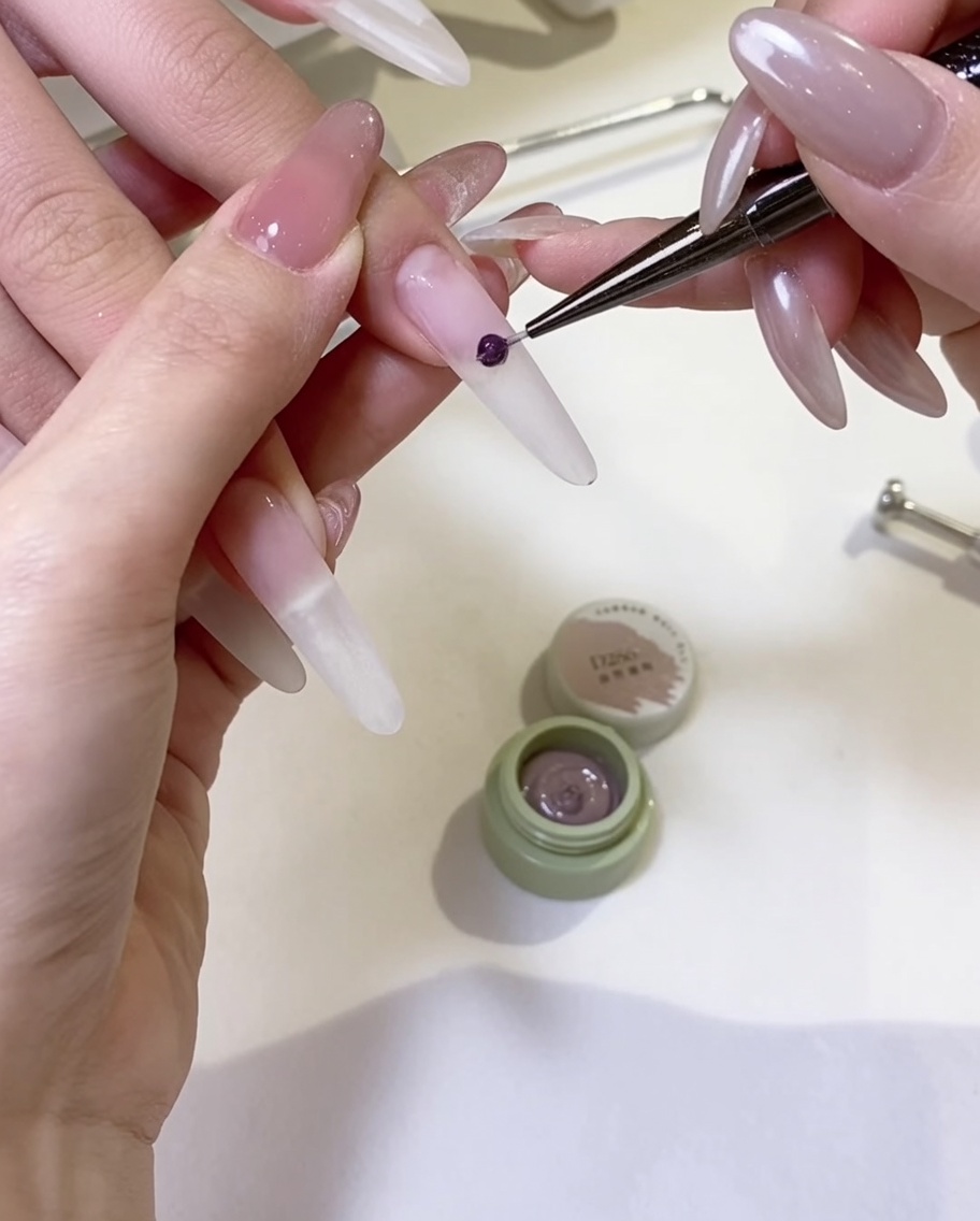 Un pennello da gel che stende uno strato uniforme di smalto gel nude sulla superficie dellunghia.