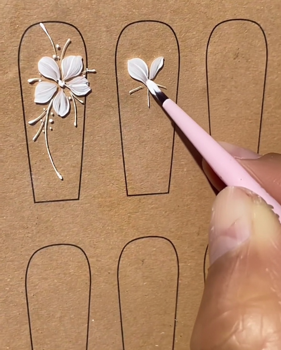 Un pennello modella con cura un terzo petalo di gel bianco come parte del design del fiore a cinque petali.