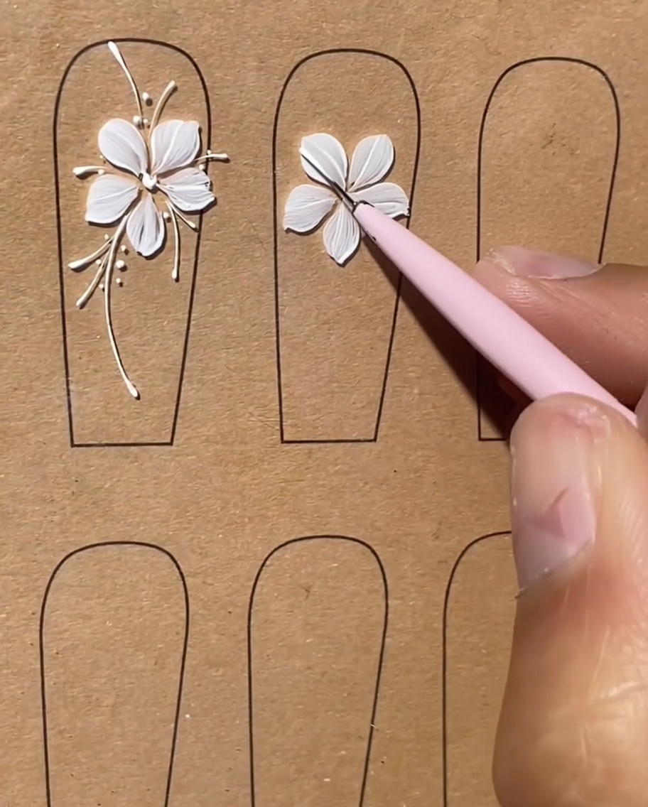 Ununghia con un design floreale bianco caratterizzato da linee bianche lunghe e sottili che si estendono verso lesterno come steli.