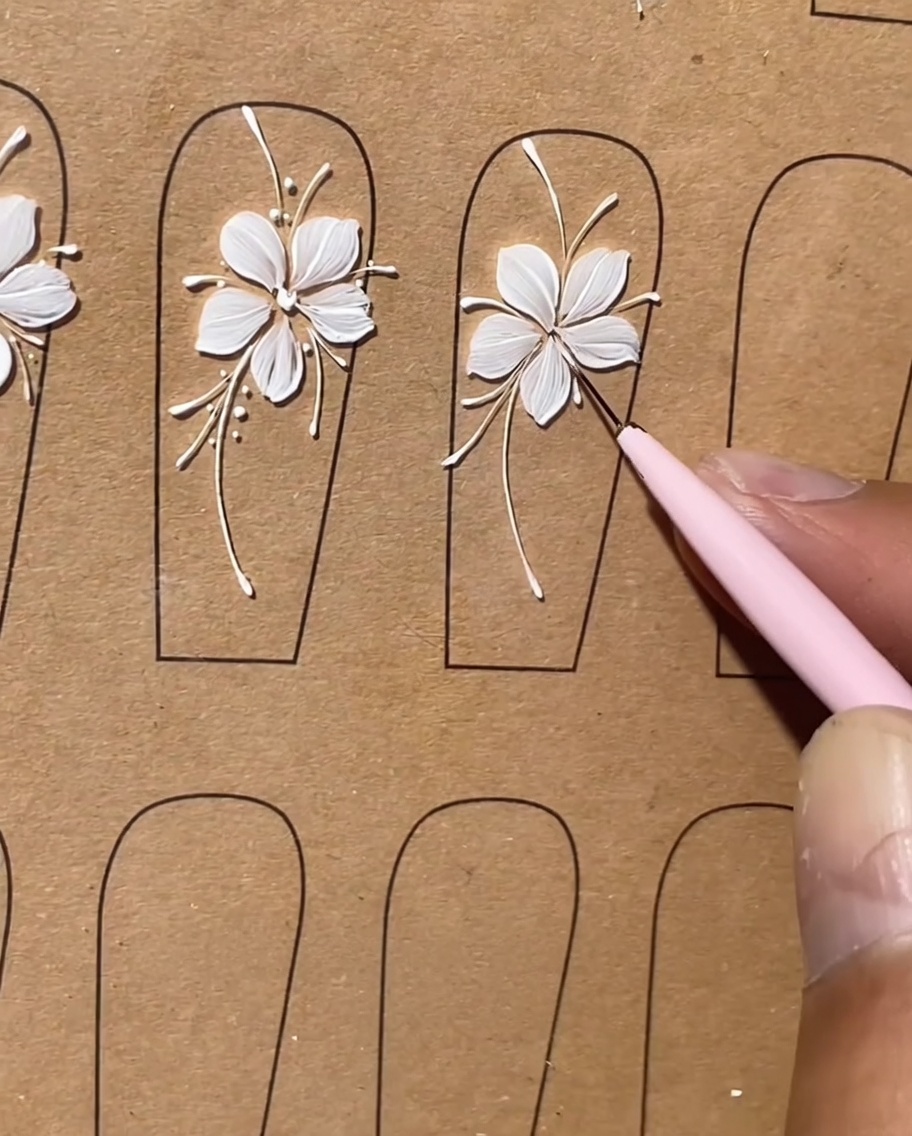 Inquadratura di dettaglio che mostra piccoli punti bianchi applicati come punti luce lungo le linee di un disegno floreale per unghie.