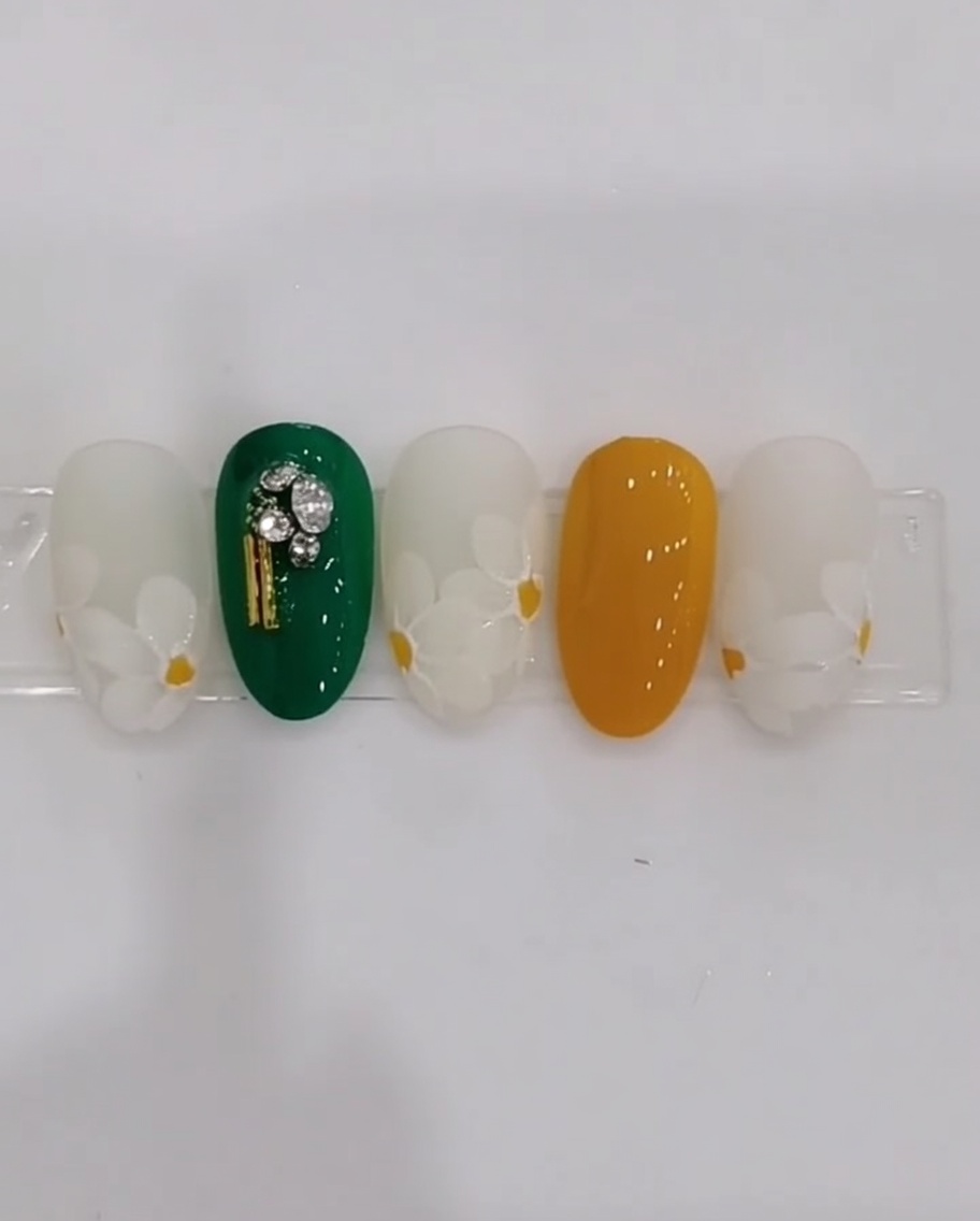 Primo piano di ununghia che mostra petali di margherita bianca dipinti a strati sovrapposti su una base latte.