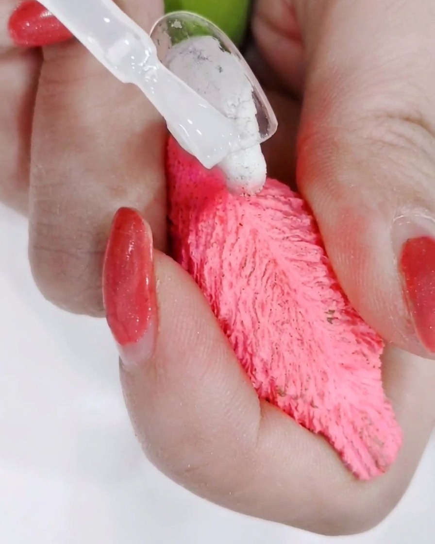 Una mano posizionata sotto una lampada professionale con la luce che polimerizza il top coat appena applicato.