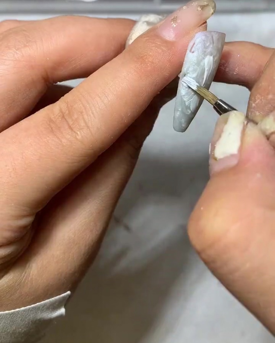 Un dettaglio che mostra la punta di un pennello liner che assottiglia lestremità di un petalo di margherita bianco.