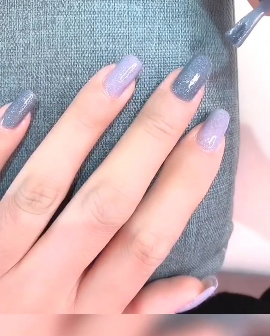 Primo piano di ununghia con due strati di smalto gel grigio, che appare opaca e liscia.