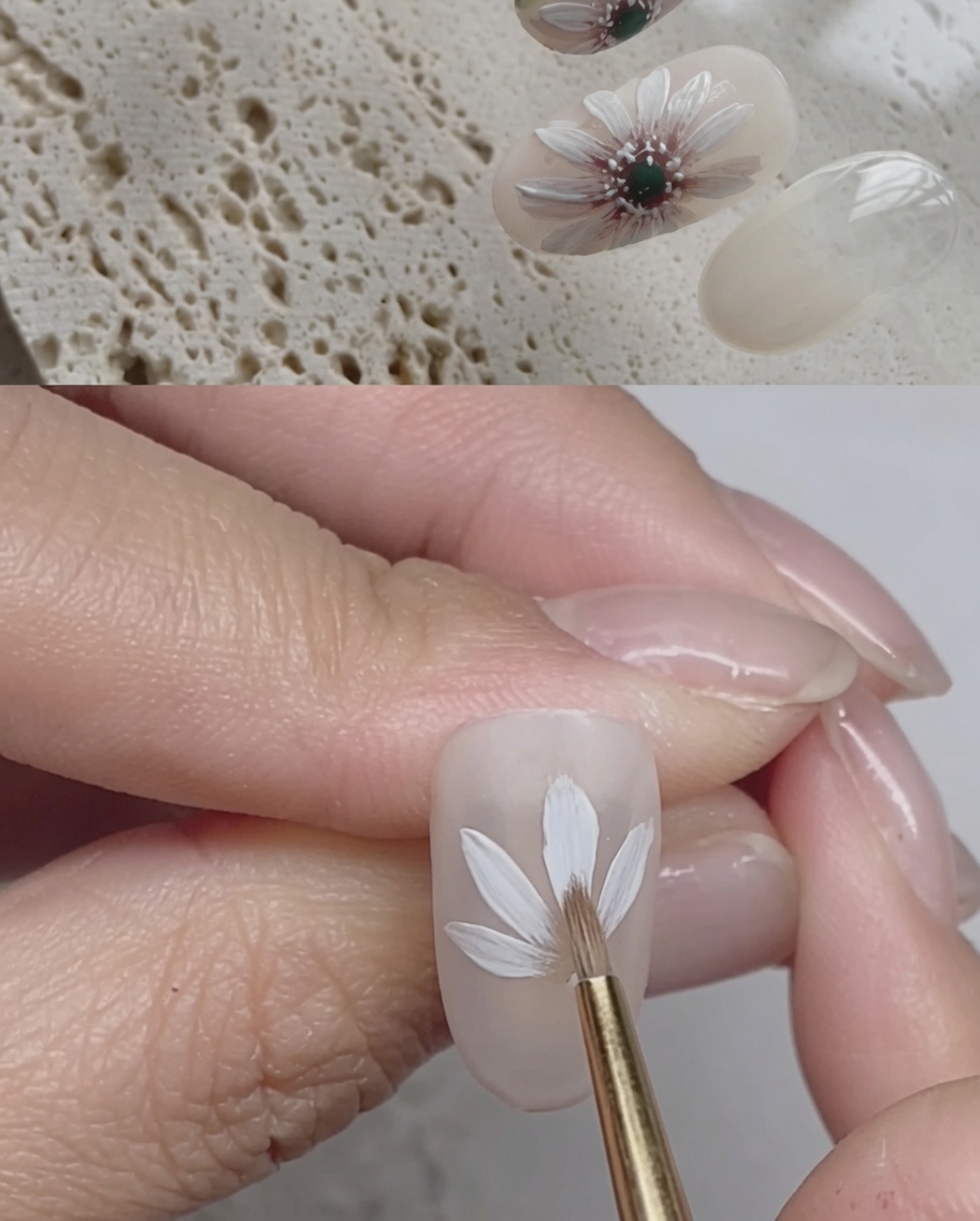 Primo piano di ununghia che mostra tratti di pennello con gel bianco che creano un secondo strato di petali di margherita sopra il primo.