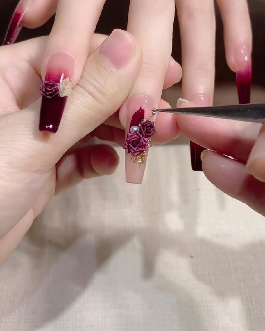 Un pennello sottile da dettaglio viene utilizzato per spostare e regolare piccole decorazioni oro e perle su ununghia.