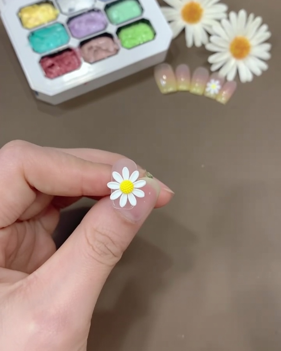 Una piccola quantità di gel giallo mescolata con base coat trasparente su una tavolozza di plastica.