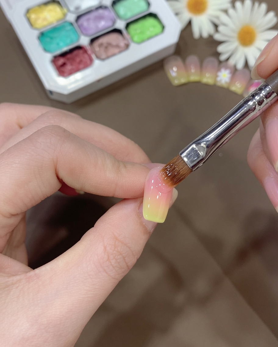 Un pennello che sfuma con cura la transizione del gel giallo sullunghia per creare un effetto sfumato liscio.
