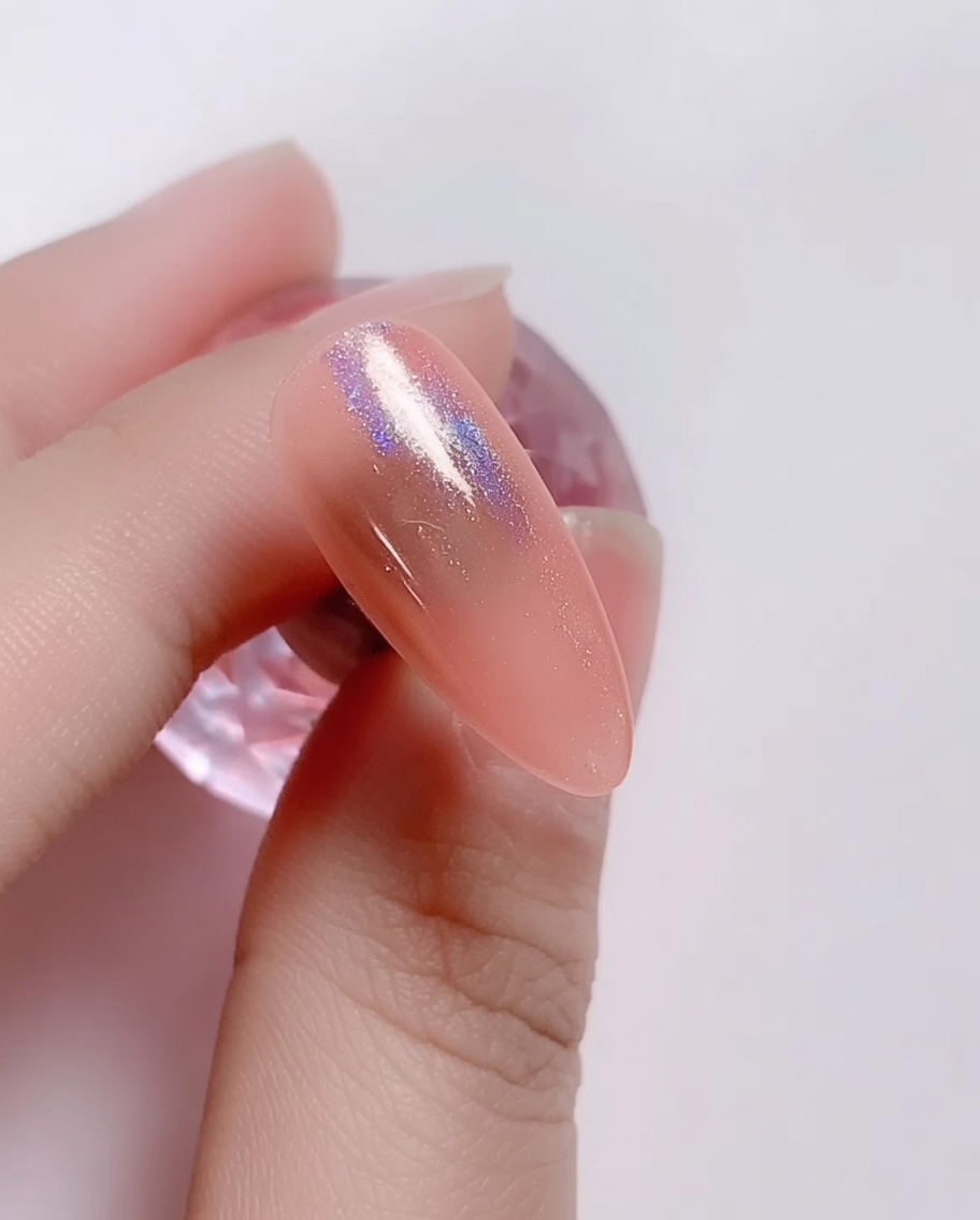 Un piccolo applicatore in spugna strofina della polvere laser iridescente su ununghia con gel rosa.
