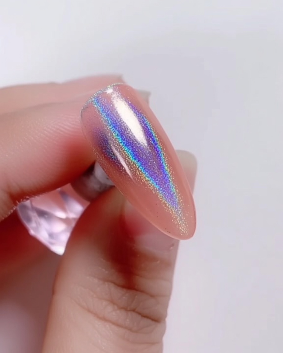 Un pennello applica un top coat trasparente e lucido sopra la polvere laser iridescente sullunghia.