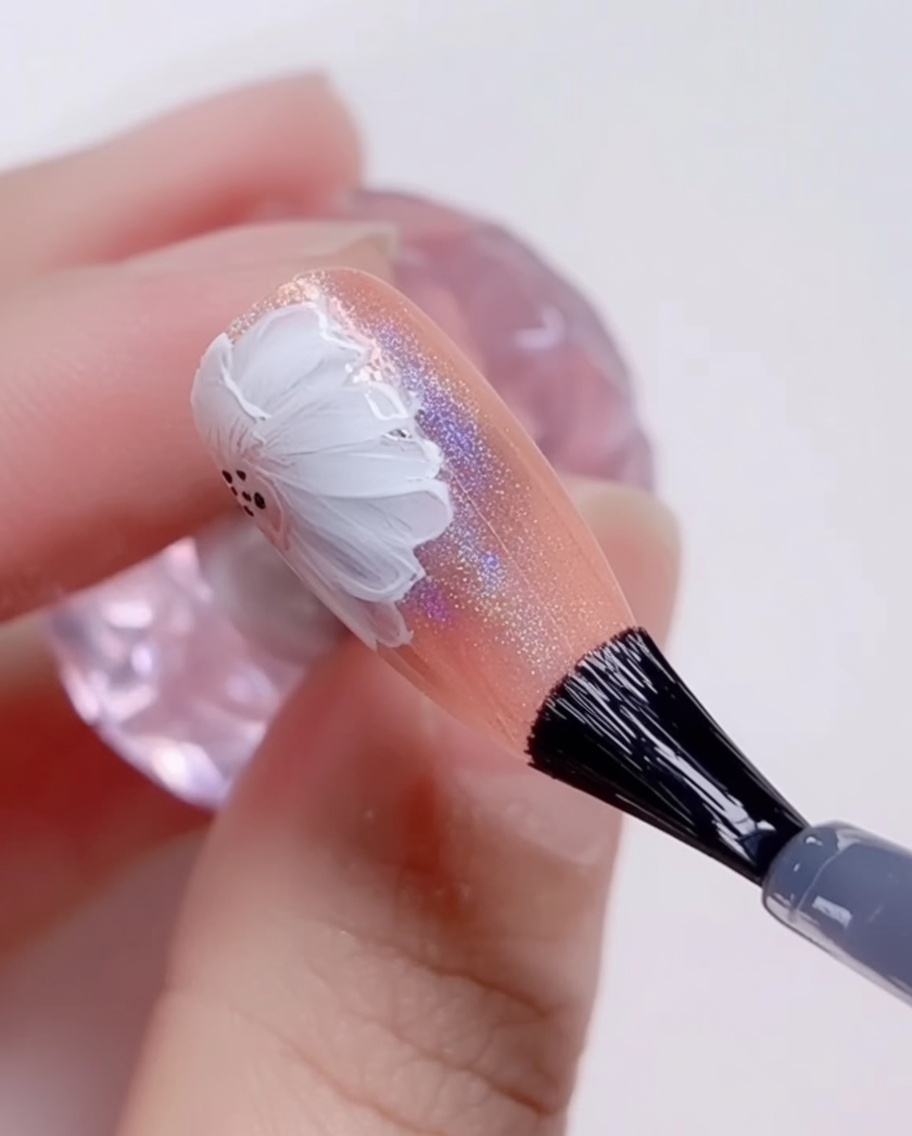 Un pennello applica un ultimo strato di top coat trasparente e lucido sopra una nail art a margherita finita.