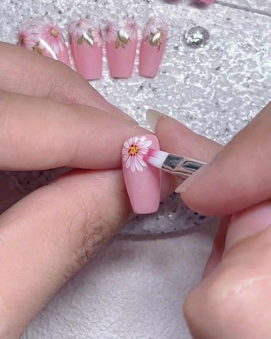 Un pennello piatto che sfuma delicatamente i bordi dei petali bianchi su ununghia rosa.