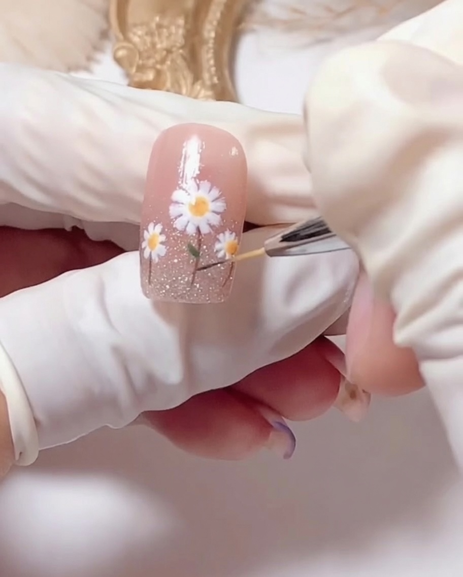 Un pennello applica un top coat trasparente brillante sulla nail art finita.