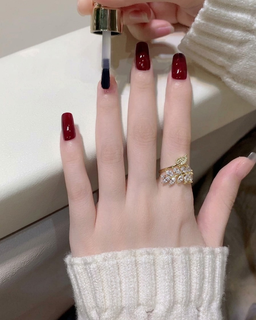 Un primo piano dellapplicazione del secondo strato di gel rosso vino scuro sullindice.