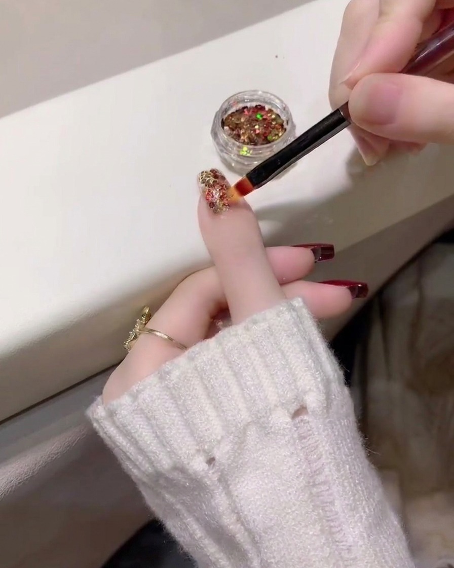 Una vista ravvicinata che mostra lapplicazione di uno strato denso di glitter multicolore sullunghia dellanulare.