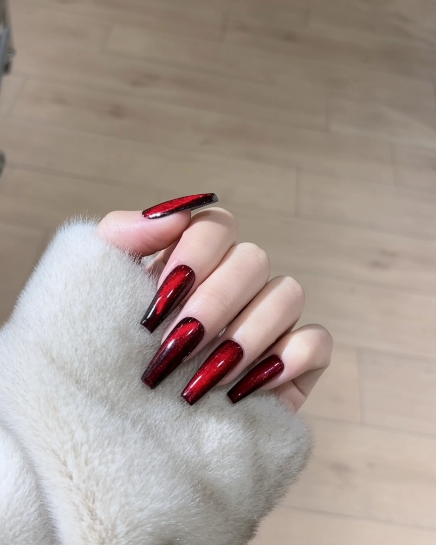 Primo piano di ununghia che viene rivestita con smalto gel magnetico rosso shimmer.