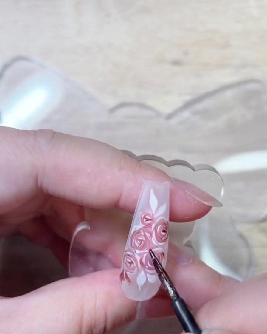 Uno scatto dettagliato del pennello che mostra il gel rosso profondo applicato per migliorare le ombre e la struttura dei petali di rosa.