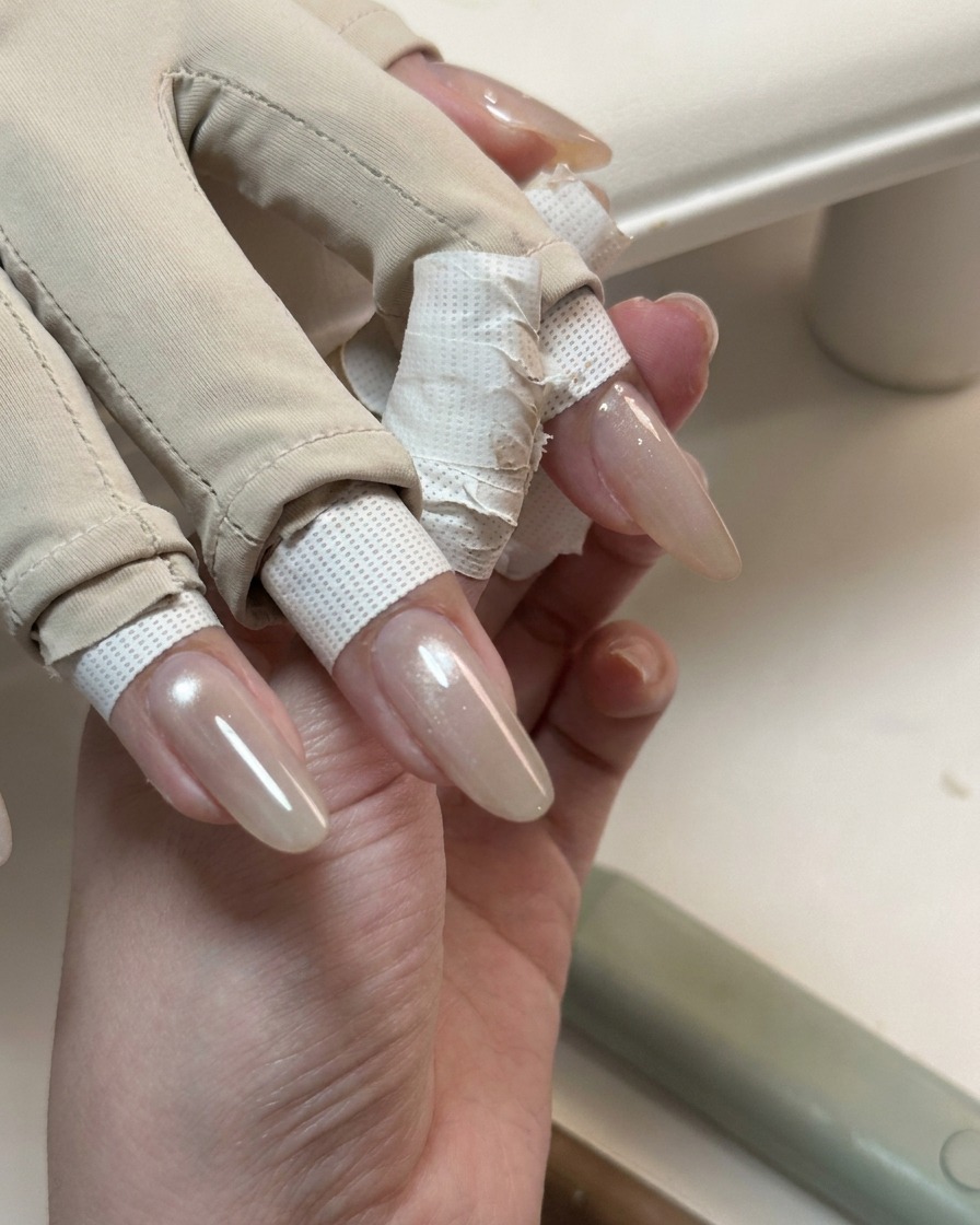Una mano mostra unghie lunghe coperte da uno strato di gel cat-eye lucido e traslucido.