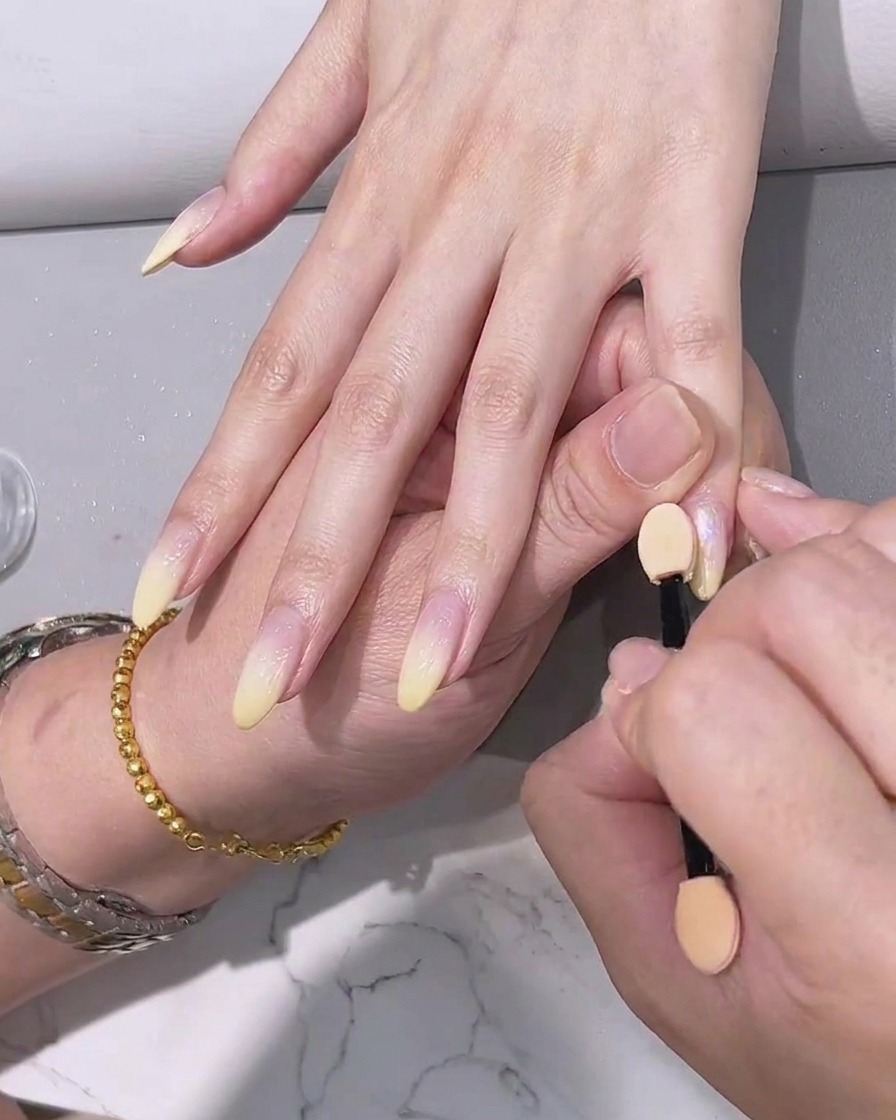 Applicazione di un top coat trasparente finale sulle unghie con effetto cromo.