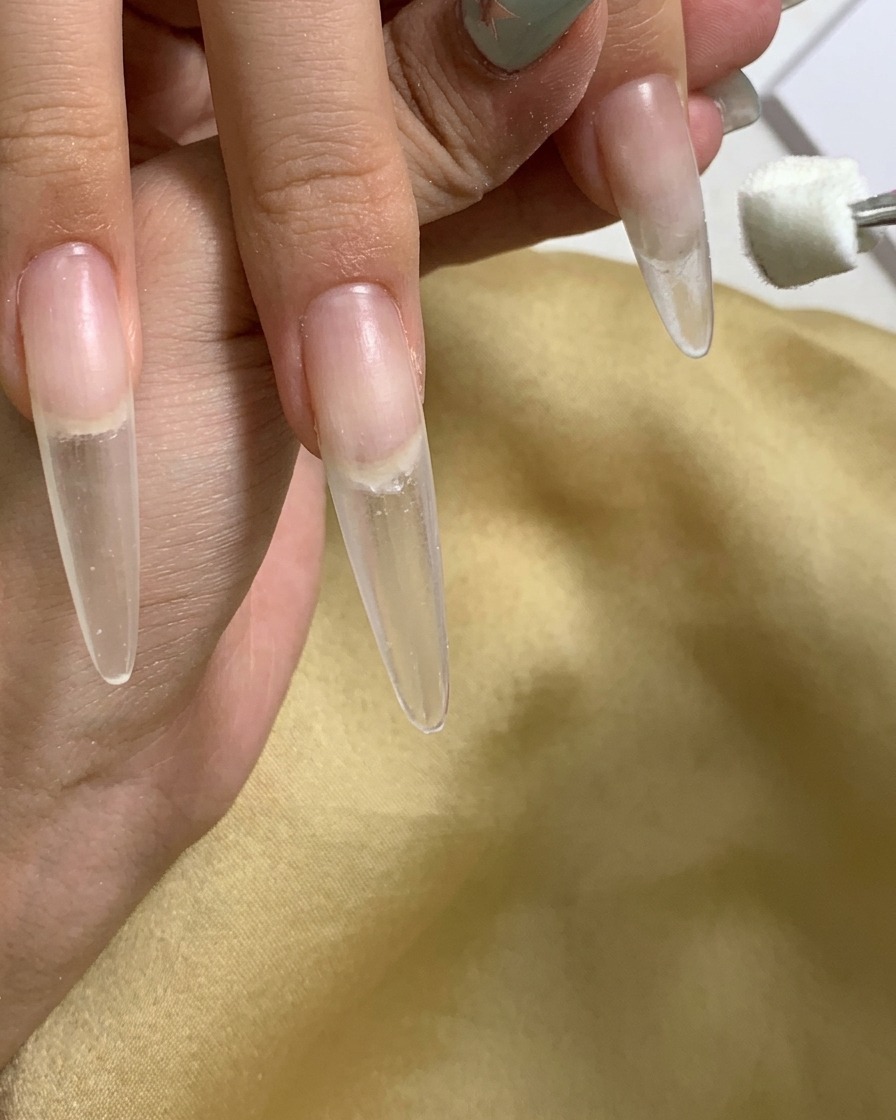 Primo piano che mostra un applicatore a spugnetta che applica il gel sulla zona delle cuticole dellunghia.