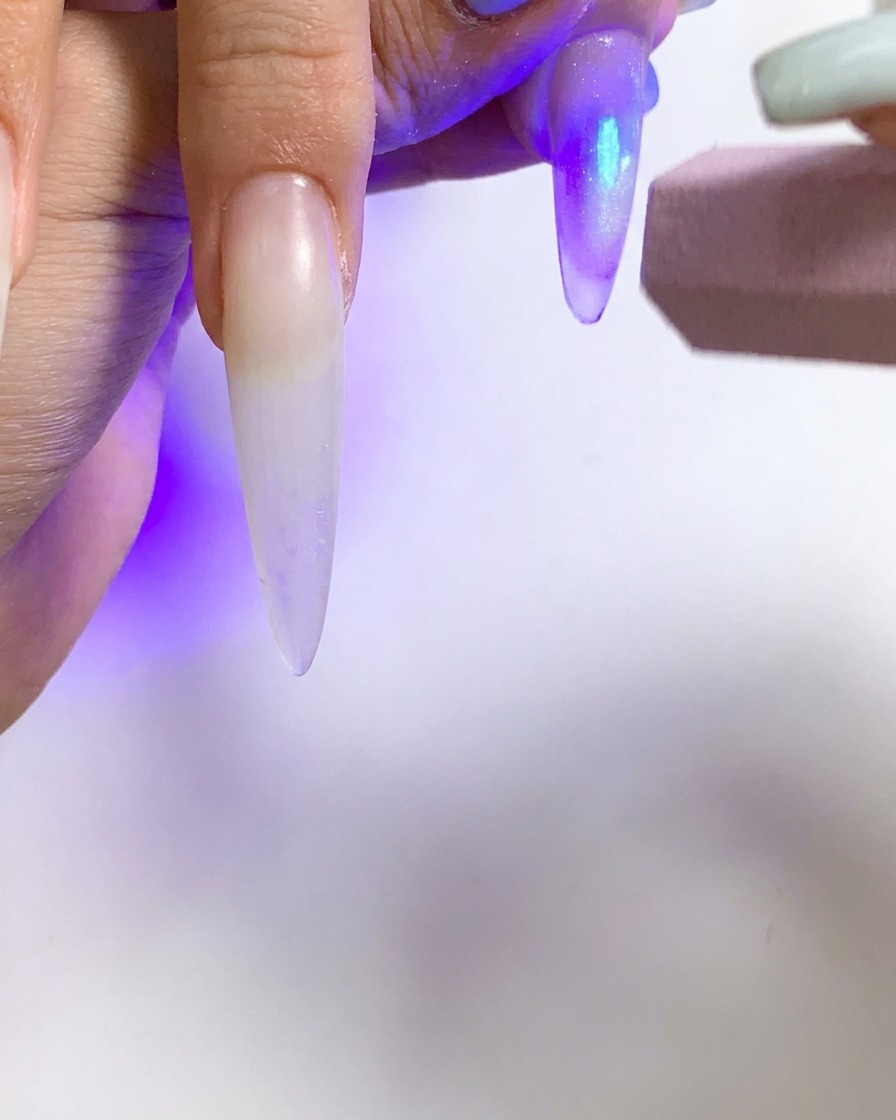 Una piccola torcia UV utilizzata per polimerizzare una singola unghia con effetto cat eye.