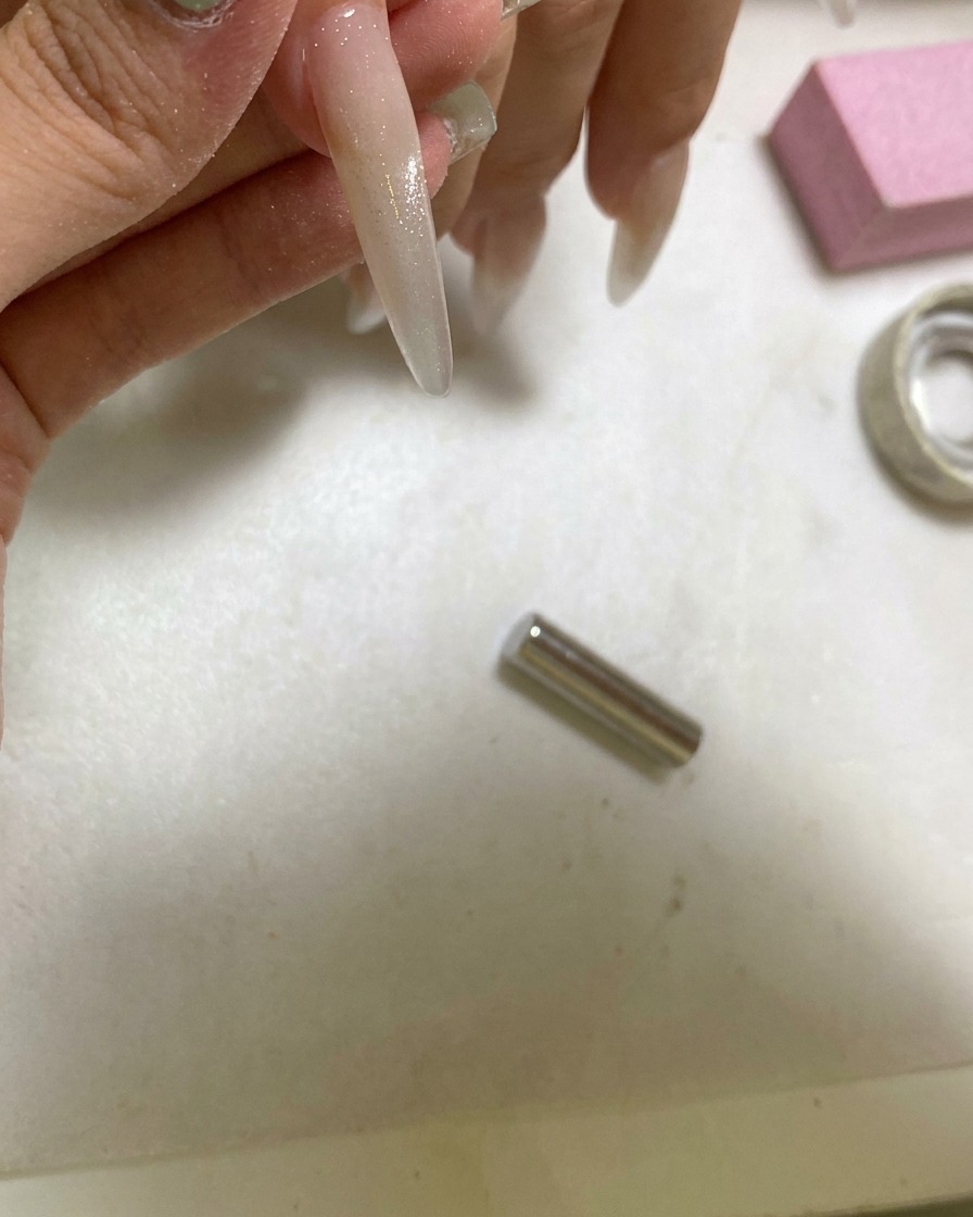Una lampada UV portatile che polimerizza ununghia decorata con un effetto cat eye a sfera di vetro.