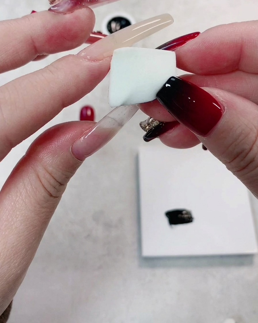 Una mano che tiene un piccolo pezzo pulito di spugna bianca ad alta densità e a pori fini.
