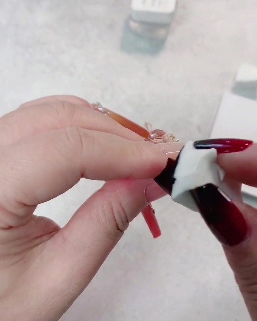 Una spugna che applica un secondo strato di gel nero sulla punta di ununghia rosso scuro per approfondire la transizione sfumata.