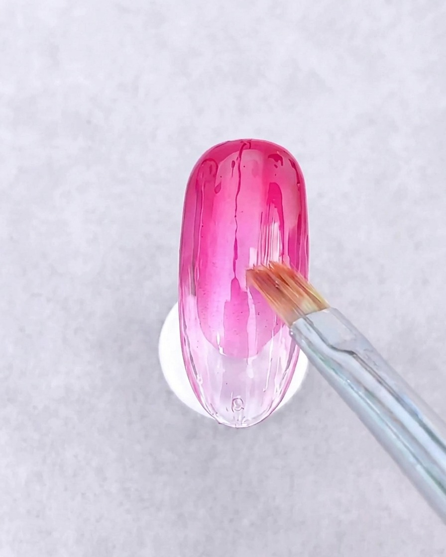Una pinzetta che posiziona piccoli pezzi geometrici di carta di vetro e sottili linee metalliche dorate su una superficie in gel bagnata.