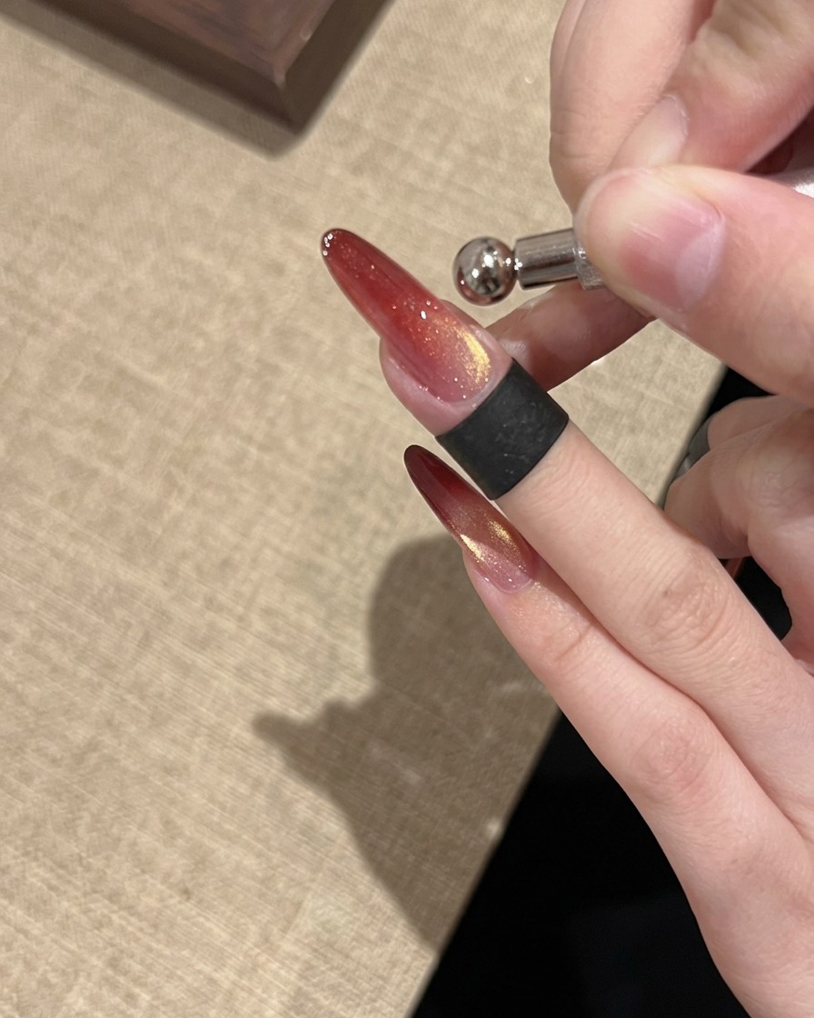 Uno strumento con magnete ad anello utilizzato per modellare un riflesso cat eye a goccia di vetro luminoso e concentrato sullunghia.