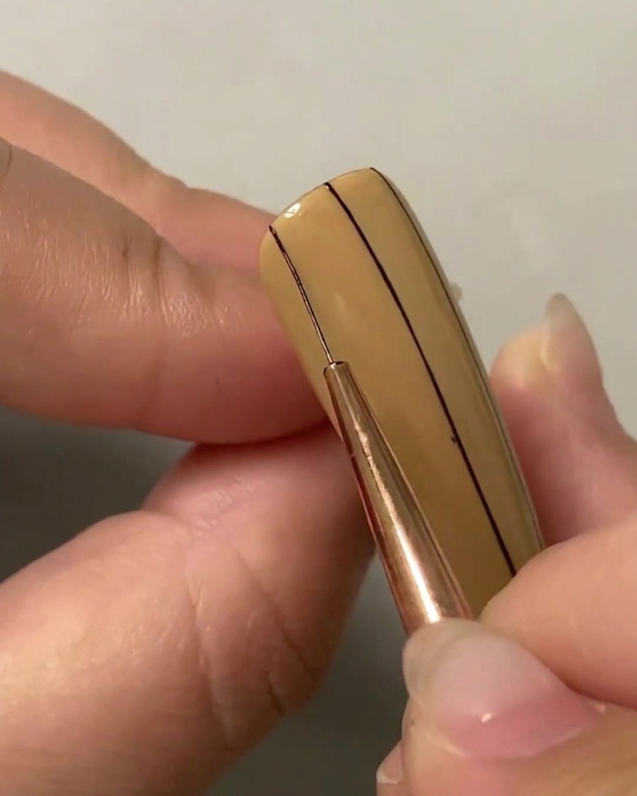 Un pennello liner che disegna una seconda linea verticale parallela sul lato sinistro dellunghia.